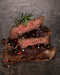 Beef rump steak on black stone table, top down, close-up.