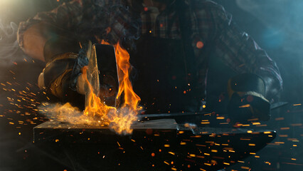 Close-up of blacksmith forging glowing hot iron on anvil with flying sparks