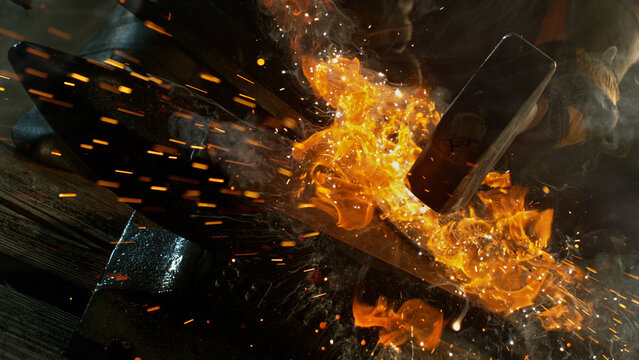 Close-up of blacksmith forging glowing hot iron on anvil with flying sparks