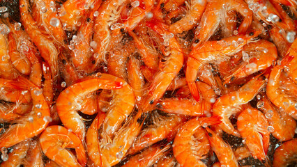 Falling tasty orange prawns into water, close-up