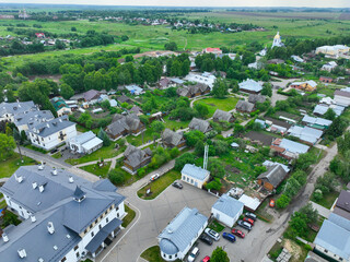 A wide aerial shot of a residential area in Suzdal, showing a mix of modern houses and traditional wooden houses, with a church tower in the distance.