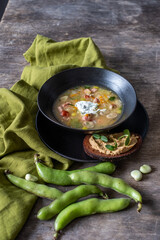 Fresh vegetable soup served in a black bowl with a side of hummus on toasted bread, garnished with herbs, showcasing healthy nutrition and aromatic flavors