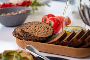 Freshly baked dark full grain bread slices arranged on a natural wooden platter with healthy ingredients and copy space for culinary design concepts