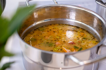 Fresh vegetable soup simmering in a stainless steel pot, showcasing vibrant colors and aromatic herbs, representing healthy cooking and nutrition concepts