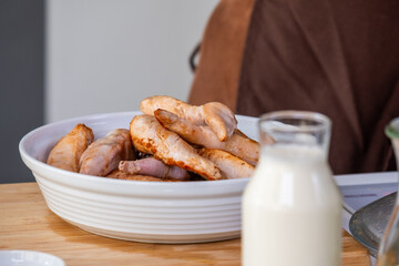 Freshly cooked chicken pieces served in a white bowl alongside a glass of milk, showcasing the culinary preparation process and inviting presentation for food enthusiasts