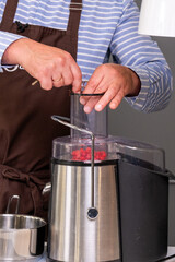 Hands of a chef in a brown apron using a food processor to combine ingredients, showcasing modern kitchen tools for efficient cooking and meal preparation with copy space