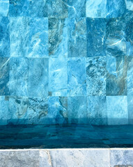 A top-down view of a swimming pool lined with square blue tiles.