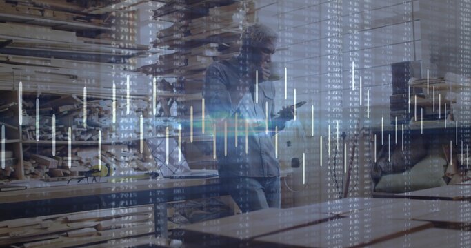 Craftsman wearing denim shirt lifting mug and checking smartphone in woodshop, with lumber tools