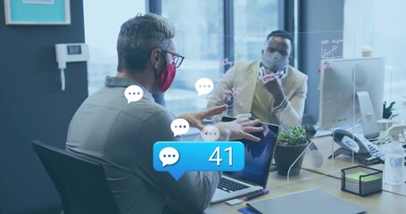 Discussing ideas two colleagues wearing masks gesturing in office, with laptop, scribbled partition