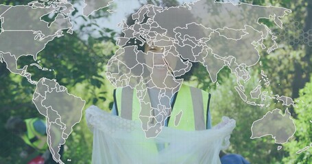 Collecting volunteer holding white bag in wooded park, wearing neon vests gloves, with map overlay