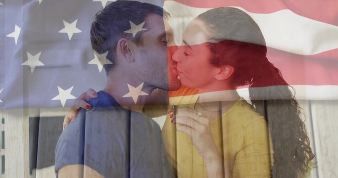 Kissing couple on wooden slats showing engagement ring and painted nails under American flag overl - Powered by Adobe
