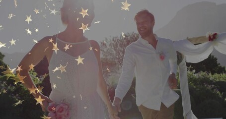 Walking couple in wedding attire holding hands at wedding, with arch, pink bouquet, golden sparkles