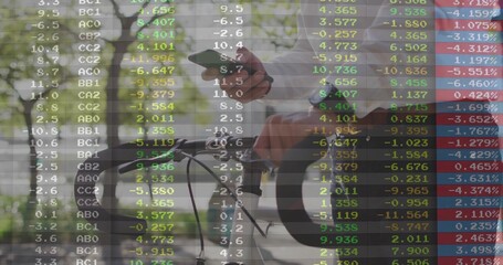 Gripping bicycle handlebars, Asian commuter checking smartphone on park trail, market data overlay