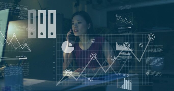 Analyzing data while talking on smartphone at modern office desk, displaying floating graphs