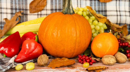 Festive autumn composition with pumpkins, seasonal vegetables and autumn leaves on wooden background. Thanksgiving celebration concept. Close-up.