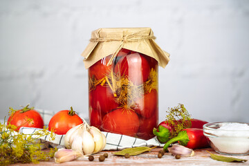 Delicious pickled homemade tomatoes in jar on a wooden background. Traditional autumn food storage. Organic farm vegetables in marinade. Close-up.