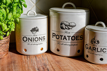 Kitchen worktop with ceramic pots for potatoes, garlic, and onions.