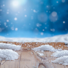 Wooden surface covered with snow with empty copy space for product placement with blurred dark blue frosty winter snowing background. Seasonal advertising, nature, winter concept.