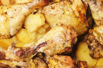 Baked chicken drumsticks with potatoes. Homemade roasted meat food closeup. Tasty cooked meal for dinner. Golden roasted chicken in pan. Delicious traditional homemade cooking.