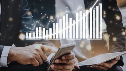 A businessman engages with a smartphone and tablet, surrounded by digital charts and graphs, illustrating financial growth and market analysis in a modern office setting. Copula