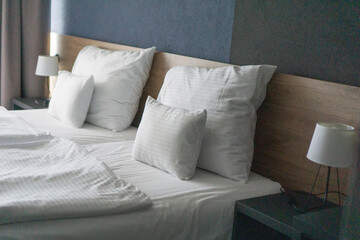 Clean bed with white pillows and duvet in a stylish bedroom, concept of home comfort, hotel industry, interior design