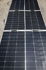 Detailed photograph of photovoltaic solar panels laid out under direct sunlight on an outdoor surface. Represents renewable energy, sustainability, and environmentally friendly power generation.