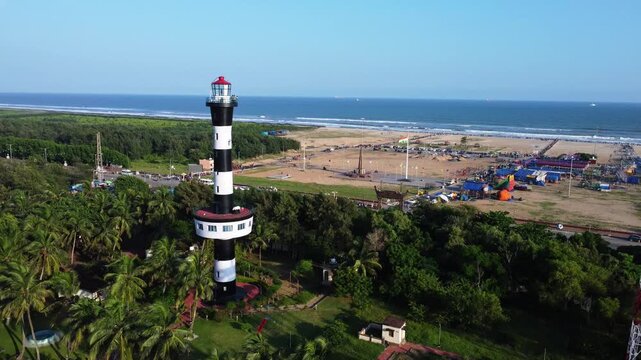 A historic lighthouse tower stands on a public beach, guiding ships through the waves on indian coast. Indian lighthouse tower