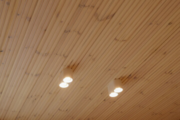 Wooden ceiling design with aligned planks and minimalist light bulbs. High quality photo