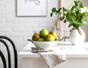 Fresh pears and apples in a colander on a kitchen table