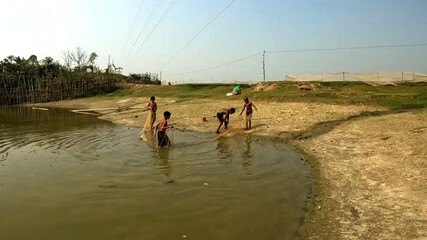 Rural Fishing Scene with Children Near Calm Waters Casting Nets on a Sunny Day Along Riverbanks