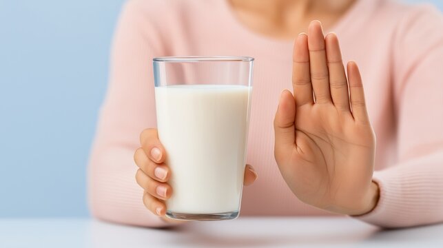 Woman refusing glass of milk with hand gesture, concept of lactose intolerance - Powered by Adobe