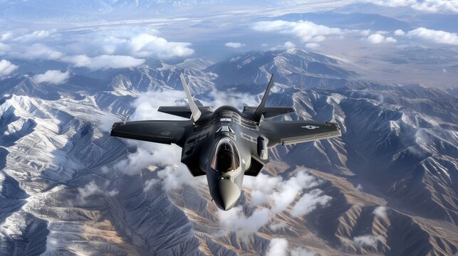 Striking front view of f 35 fighter jet flying above clouds with snow capped mountains below