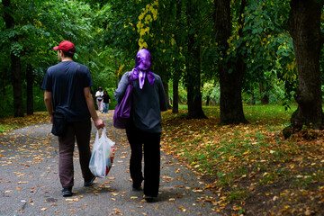 Fototapeta premium Couple st Rolling through park adorned with autumn leaves, enjoying a peaceful leisurely walk in nature
