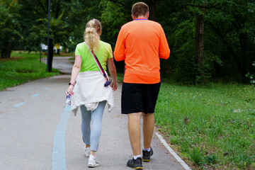 Couple walking on a scenic path in a park during a sunny afternoon, enjoying an active outdoor lifestyle together