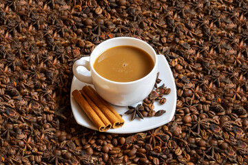 A white cup with a saucer and coffee and coffee beans on a brown cloth background