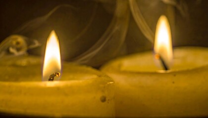 Two yellow candles burning softly in the dark