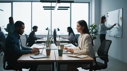 A busy and collaborative office environment featuring diverse individuals working at desks with computers and a woman presenting at a whiteboard. - Powered by Adobe