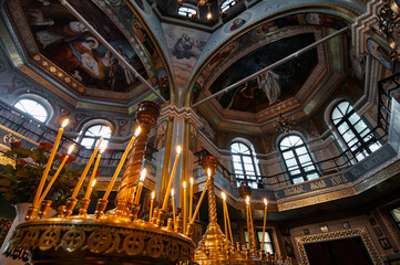 Beautifully decorated church interior featuring ornate murals, glowing candles, and architectural...