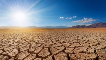 Barren Desert Landscape With Cracked Ground And Sunlight Rays Against A Blue Sky