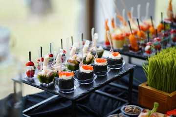 Canapés with caviar, vegetables and seafood in transparent mini-containers, wedding buffet.