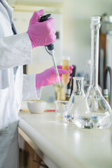 Scientist working with pipette in laboratory using protective gloves and glassware