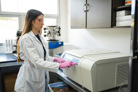 Female scientist operating centrifuge machine in modern lab