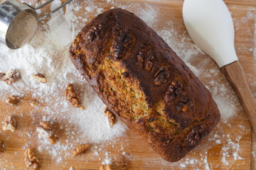 Homemade banana bread with walnuts on floured wooden board