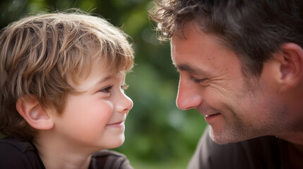 Smiling father and son sharing a joyful moment outdoors with greenery in the background