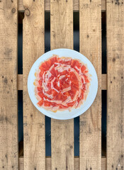 VIEW OF A PLATE OF CURED SPANISH HAM ON AN OLD WOODEN PALLET