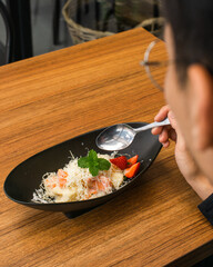 Person about to eat a dish of pasta with strawberries and mint.