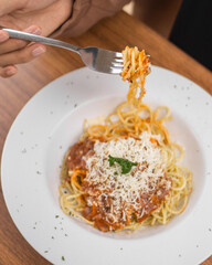 Overhead shot of spaghetti with meat sauce and grated cheese on a white plate.