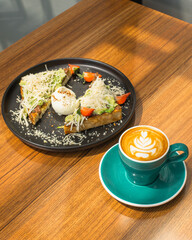 Avocado toast with poached egg and coffee on a wooden table.