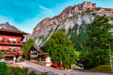 Fototapeta premium Traditional wooden chalets, adorned with vibrant flowers, line the street, creating a charming and idyllic atmosphere. The imposing mountain, with its rugged charm.