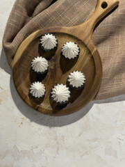 White meringues arranged on a wooden board, top view, highlighting the sweet pastry details